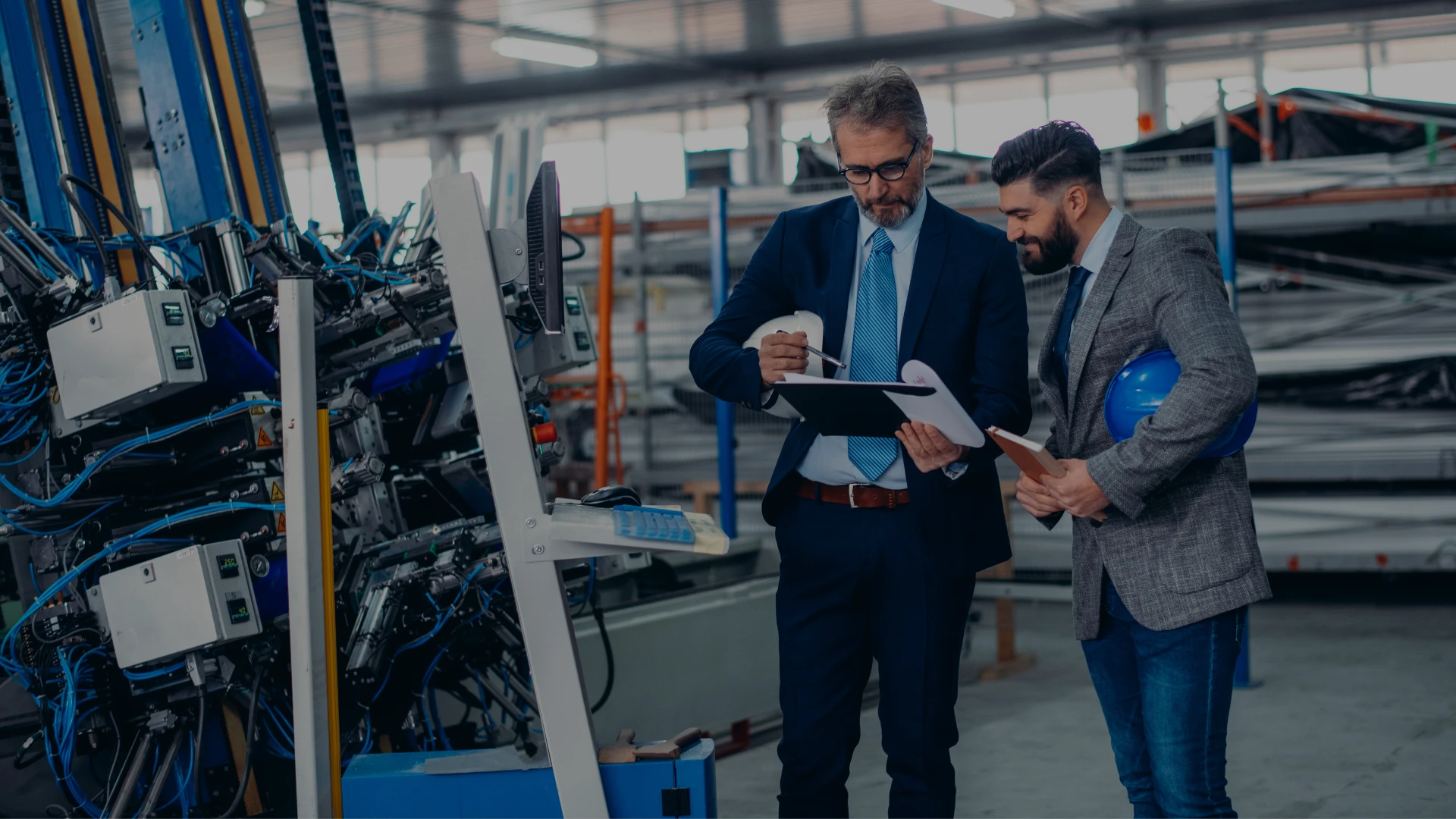 A facilities director and a building manager reviewing a scope of work on a plant floor